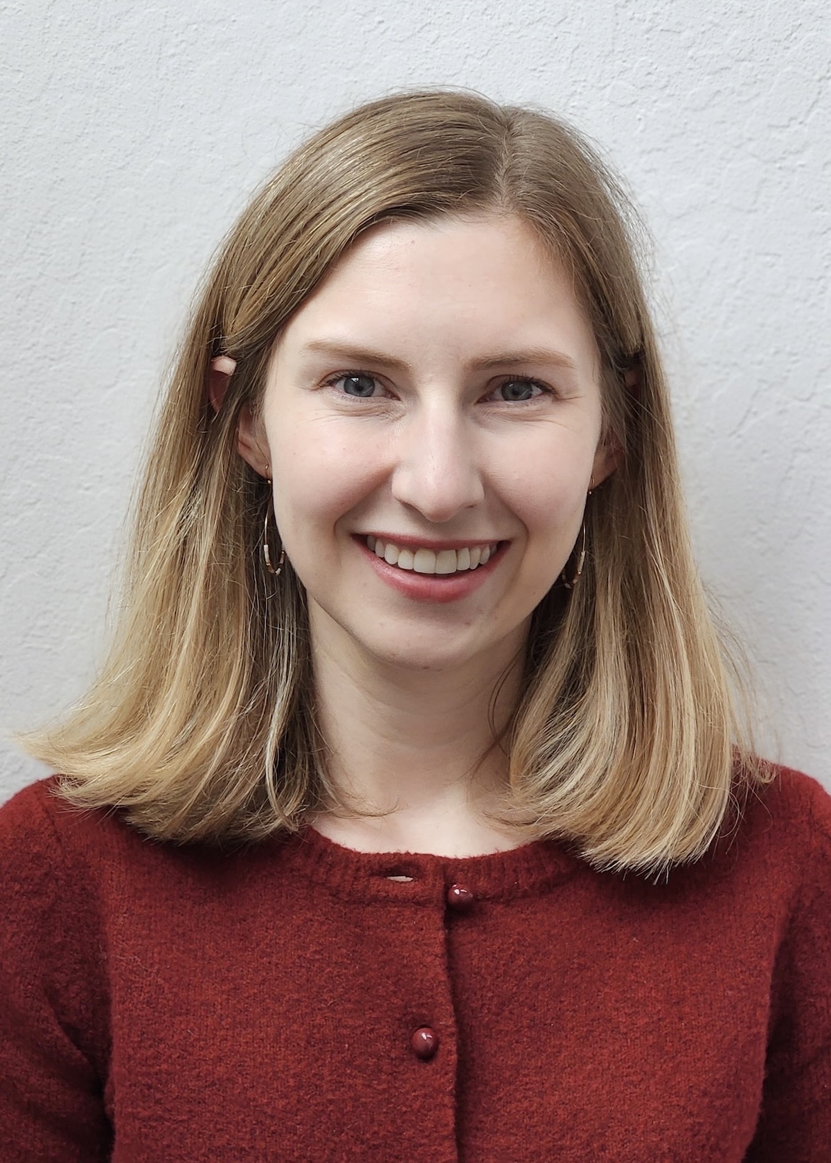 Smiling young woman, shoulder-length blonde hair, maroon sweater, portrait photograph